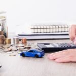man using a calculator, with stacked coins, and a notepad