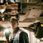 Lexus technician inspecting hybrid battery under car